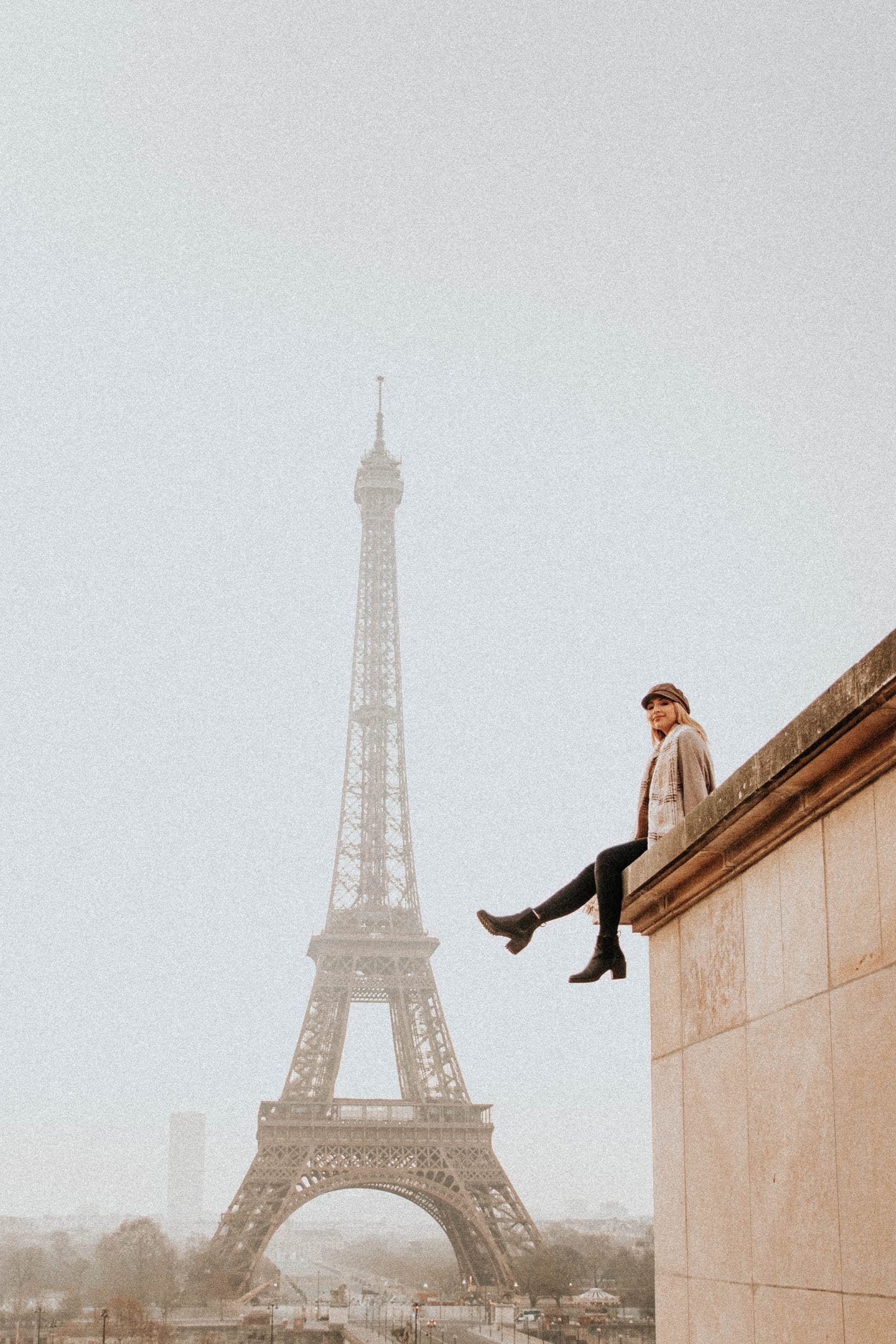 Girl on ledge in front of the Eiffel Tower